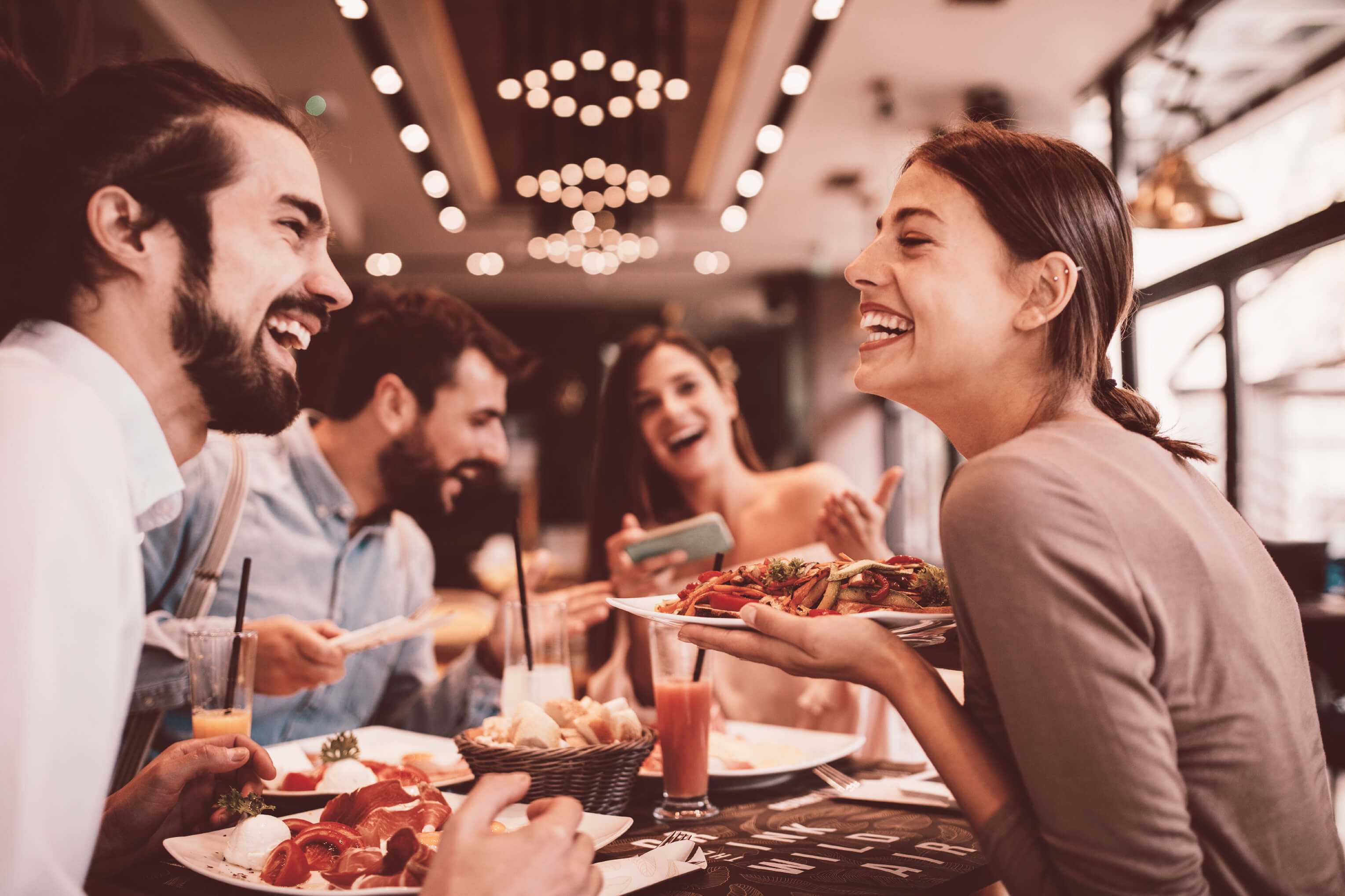 Two happy couples enjoying a meal together, talking and
laughing in a fancy restaurant, during the daytime.